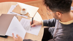From above male employee writing signature on promissory note while sitting at table