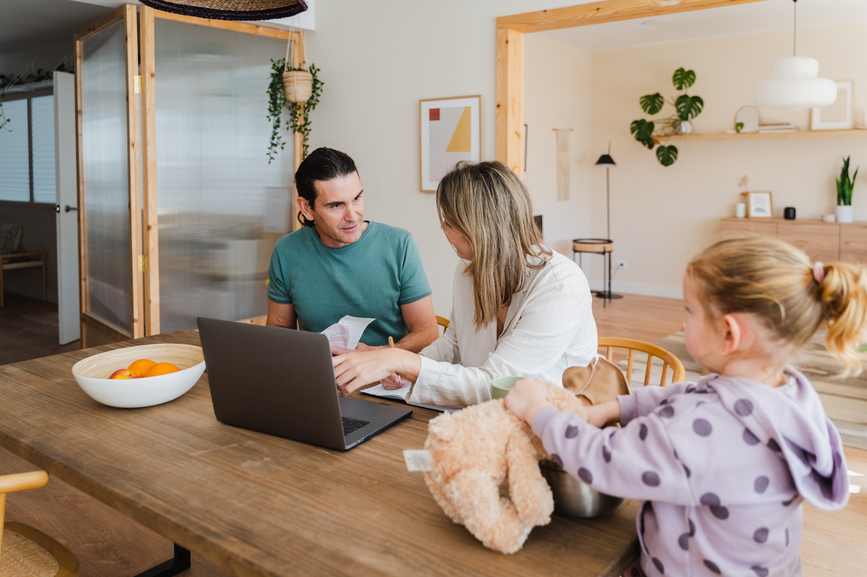 young parents calculating and managing family budget while sitting at table with laptop at home