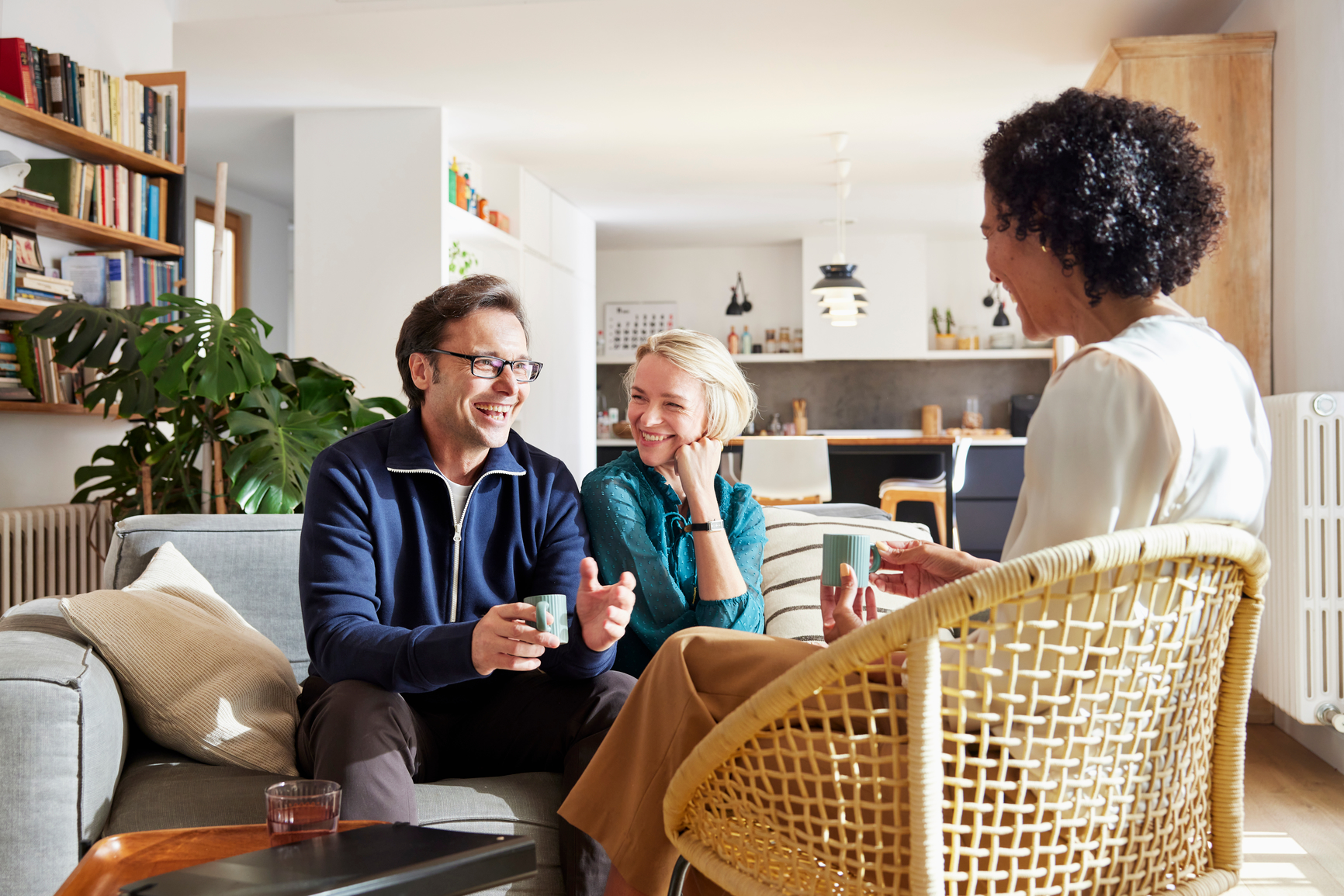 Cheerful adult couple in casual clothes having meeting with tax advisor in living room at home during daytime