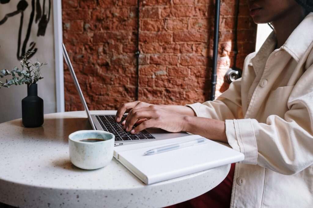 A woman working in a coffee shop on a laptop